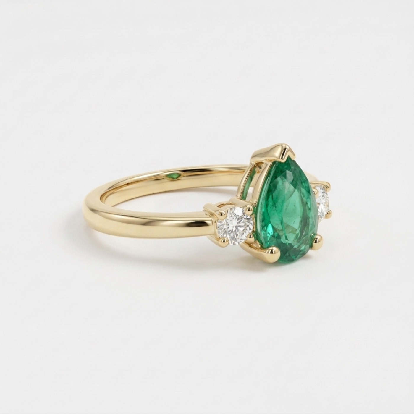 Finished pear-cut emerald ring with diamond side stones in yellow gold